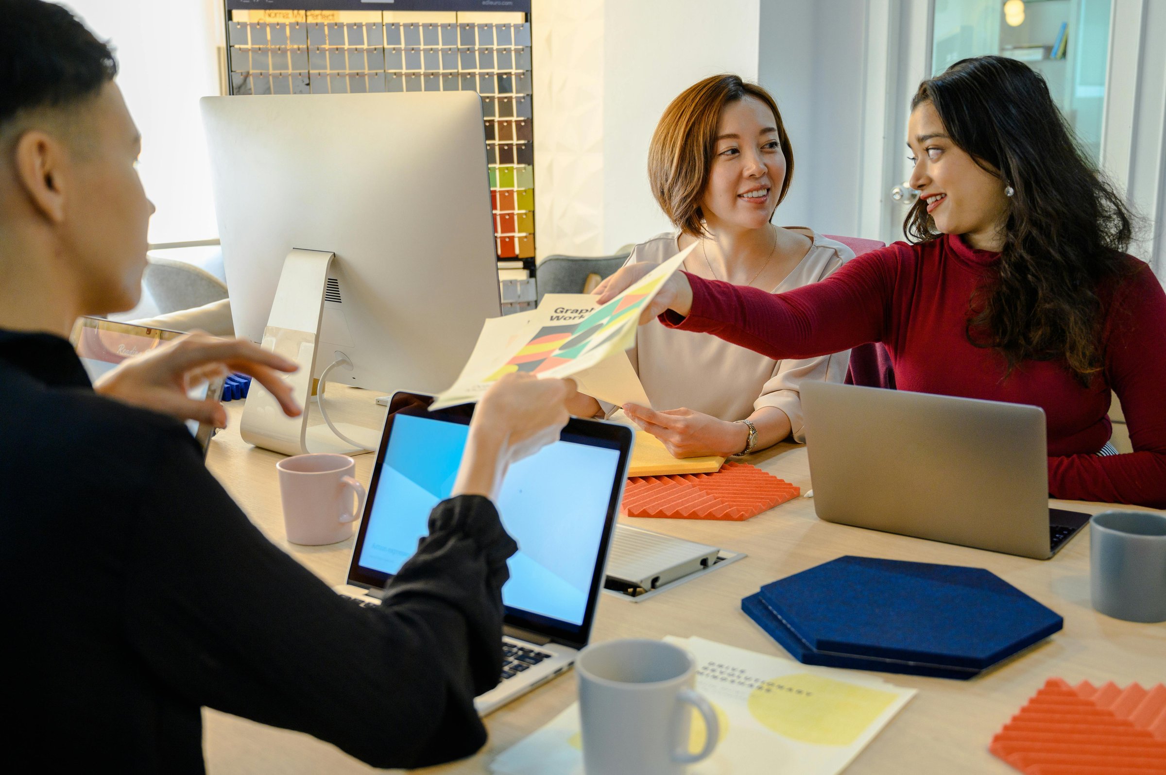 A small product team working at a shared table, laptops and notes between them.