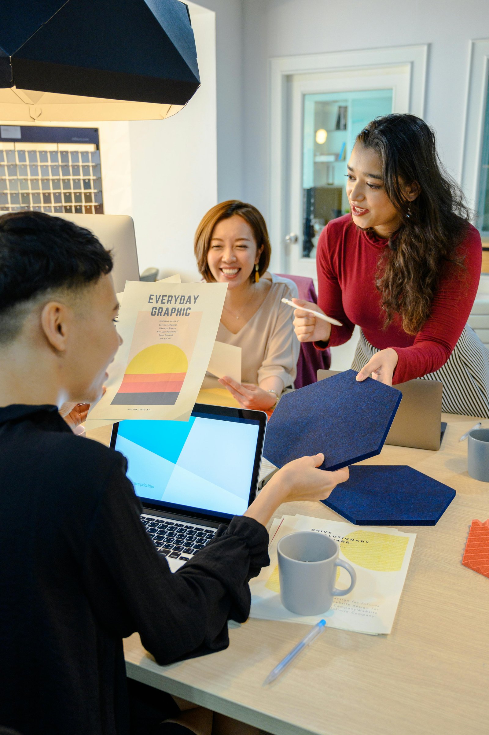 A small product team working at a shared table, laptops and notes between them.